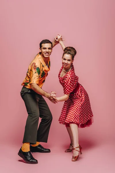 Smiling dancers looking at camera while dancing boogie-woogie on pink background — Stock Photo