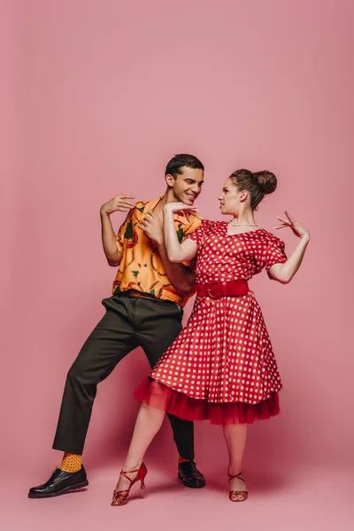 Elegant dancers looking at each other while dancing boogie-woogie on pink background — Stock Photo