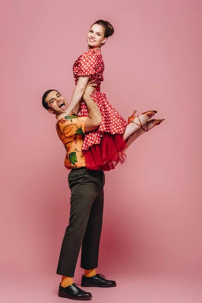 Joyeux danseur tenant partenaire tout en dansant boogie-woogie sur fond rose — Stock Photo