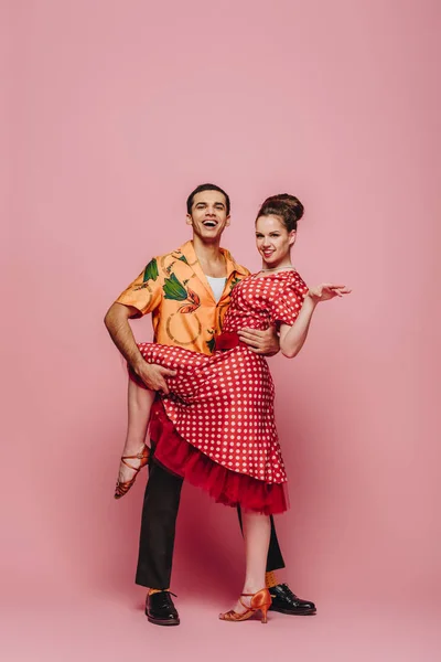 Lächelnde Tänzerin umarmt Partner, während sie Boogie-Woogie auf rosa Hintergrund tanzt — Stockfoto