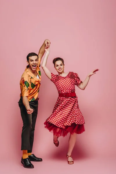 Alegres bailarines tomados de la mano mientras bailan boogie-woogie sobre fondo rosa - foto de stock