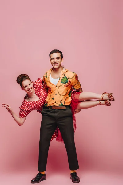 Handsome dancer holding woman while dancing boogie-woogie on pink background — Stock Photo