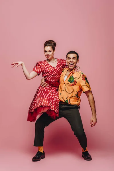 Stylish dancer holding woman while dancing boogie-woogie on pink background — Stock Photo