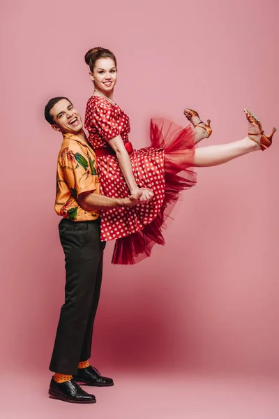 Elegante uomo che tiene donna mentre balla boogie-woogie su sfondo rosa — Foto stock