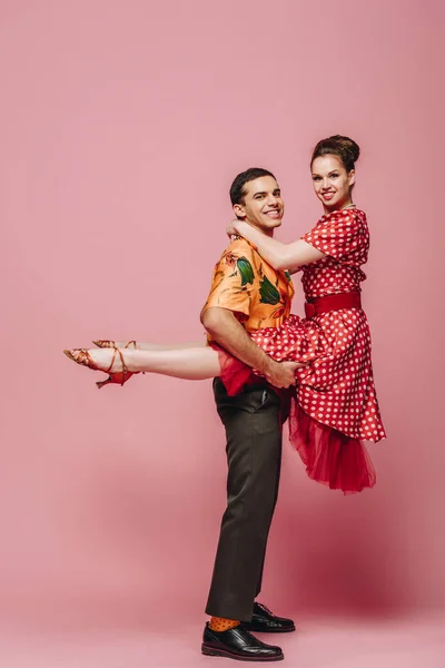 Fröhlicher Mann hält Frau beim Tanzen von Boogie-Woogie auf rosa Hintergrund — Stockfoto