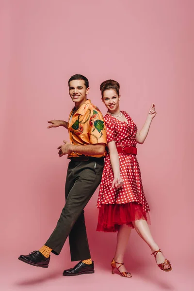 Happy dancers looking at camera while dancing boogie-woogie on pink background — Stock Photo