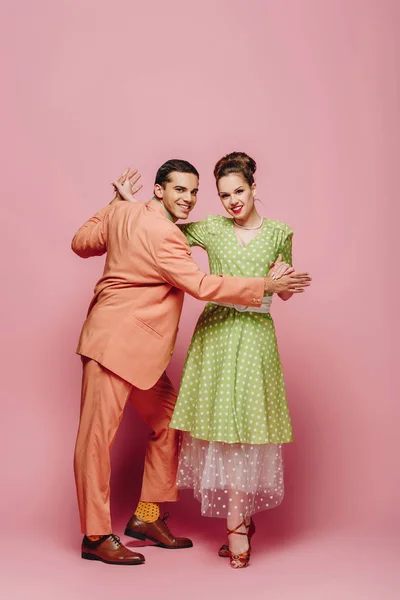 Stylish dancers holding hands while dancing boogie-woogie on pink background — Stock Photo