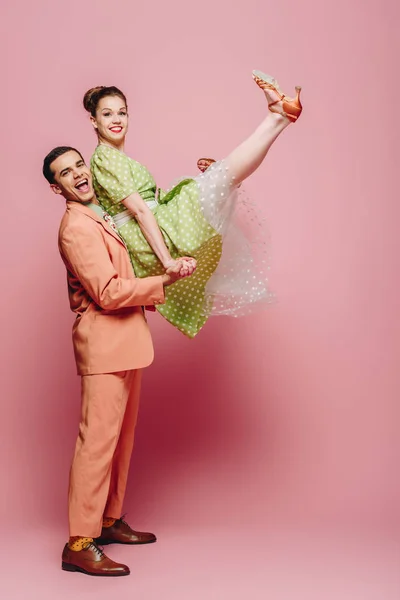 Elegant dancer holding girl while dancing boogie-woogie on pink background — Stock Photo