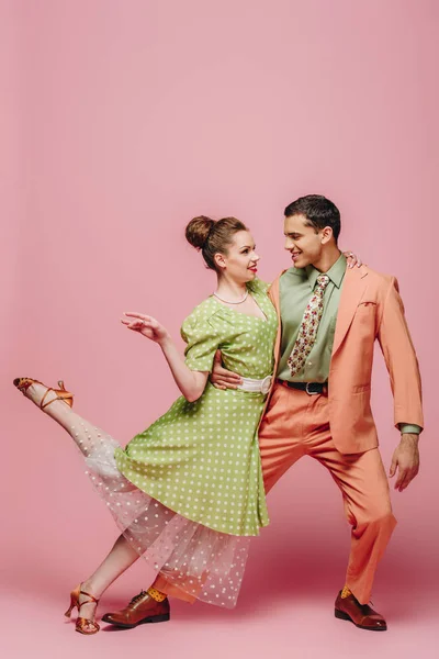 Handsome dancer hugging girl while dancing boogie-woogie on pink background — Stock Photo