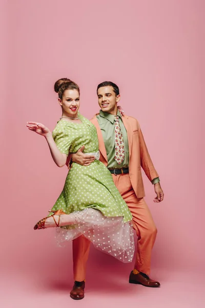 Handsome dancer hugging girl while dancing boogie-woogie on pink background — Stock Photo