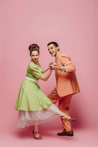 Dançarinos elegantes de mãos dadas enquanto dançam boogie-woogie no fundo rosa — Fotografia de Stock