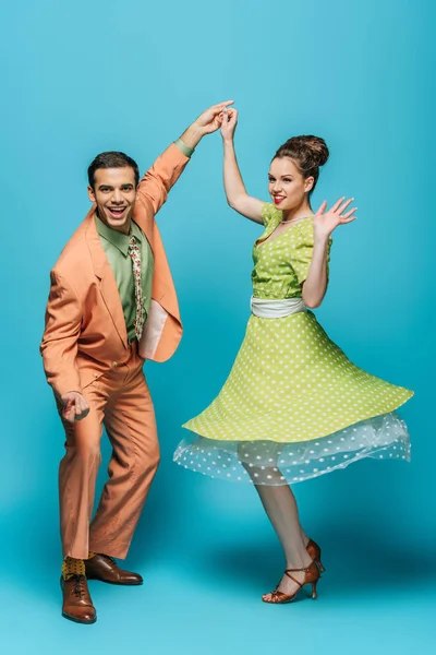 Danseurs élégants tenant la main tout en dansant boogie-woogie sur fond bleu — Photo de stock