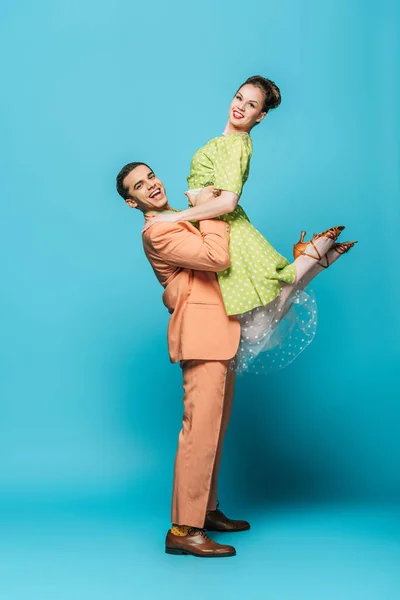 Hermosa bailarina holding chica mientras bailando boogie-woogie sobre fondo azul - foto de stock
