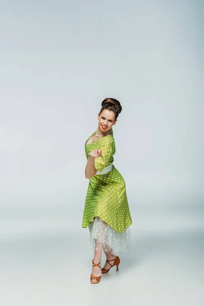 Attractive, stylish dancer looking at camera while dancing boogie-woogie on grey background — Stock Photo