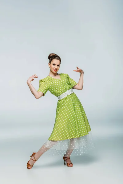 Pretty, stylish dancer looking at camera while dancing boogie-woogie on grey background — Stock Photo