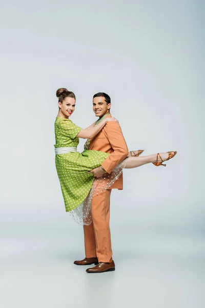 Stylish dancer holding girl while dancing boogie-woogie on grey background — Stock Photo