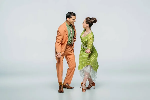 Happy dancers looking at each other while dancing boogie-woogie on grey background — Stock Photo