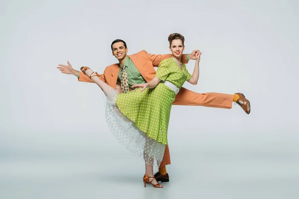 Happy dancers looking at camera while dancing boogie-woogie on grey background — Stock Photo