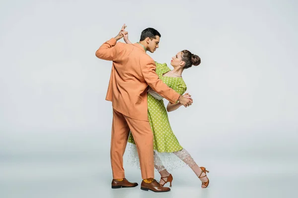 Ballerini alla moda che si guardano mentre ballano boogie-woogie su sfondo grigio — Foto stock