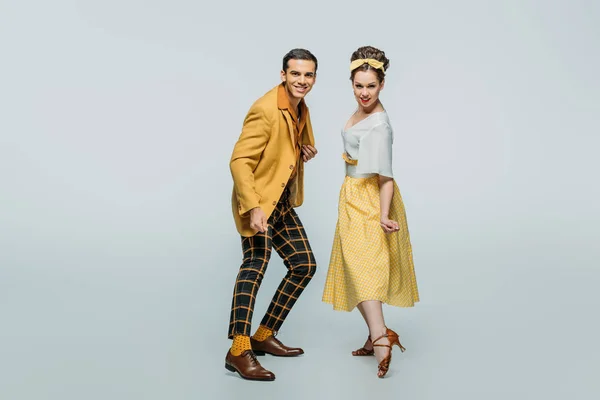 Happy dancers looking at camera while dancing boogie-woogie on grey background — Stock Photo