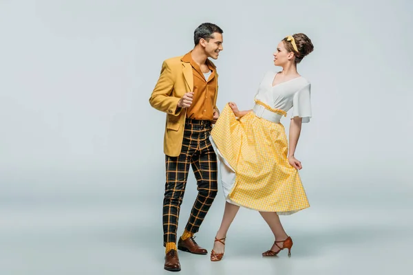 Danseurs élégants qui se regardent tout en dansant boogie-woogie sur fond gris — Photo de stock