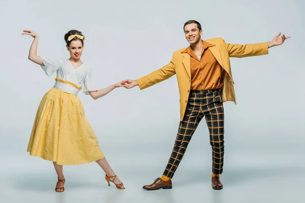 Stylish dancers holding hands while dancing boogie-woogie on grey background — Stock Photo