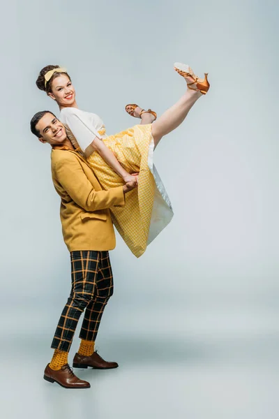 Stylish dancer holding happy girl while dancing boogie-woogie on grey background — Stock Photo