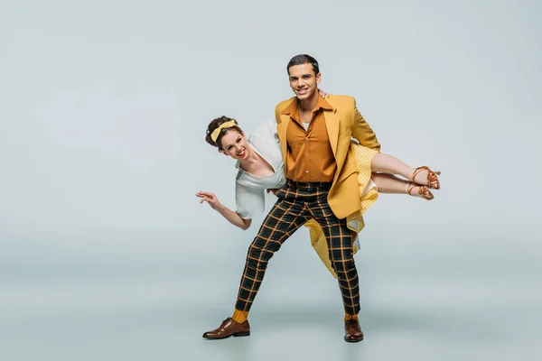 Handsome dancer holding girl while dancing boogie-woogie on grey background — Stock Photo