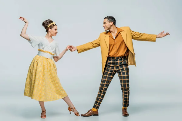 Stylish dancers holding hands while dancing boogie-woogie on grey background — Stock Photo