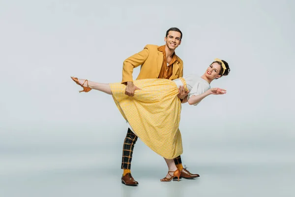 Bonito dançarino apoio parceiro enquanto dança boogie-woogie no fundo cinza — Fotografia de Stock