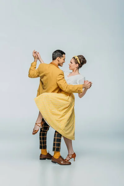 Elegant dancers holding hands while dancing boogie-woogie on grey background — Stock Photo