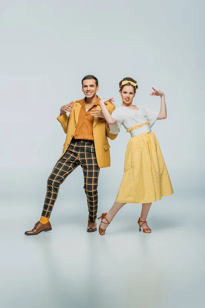 Cheerful dancers looking at camera while dancing boogie-woogie on grey background — Stock Photo