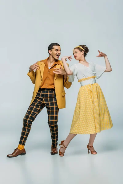 Cheerful dancers looking at each other while dancing boogie-woogie on grey background — Stock Photo