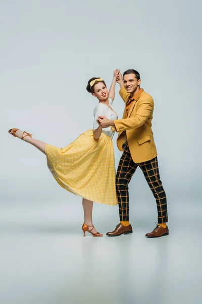 Stylish dancers holding hands while dancing boogie-woogie on grey background — Stock Photo