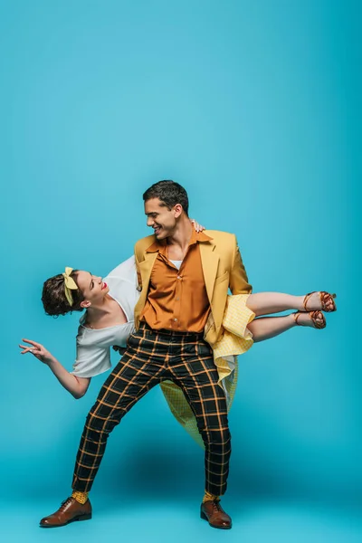 Handsome dancer holding girl while dancing boogie-woogie on blue background — Stock Photo