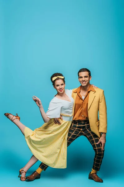 Stylish dancers looking at camera while dancing boogie-woogie on blue background — Stock Photo