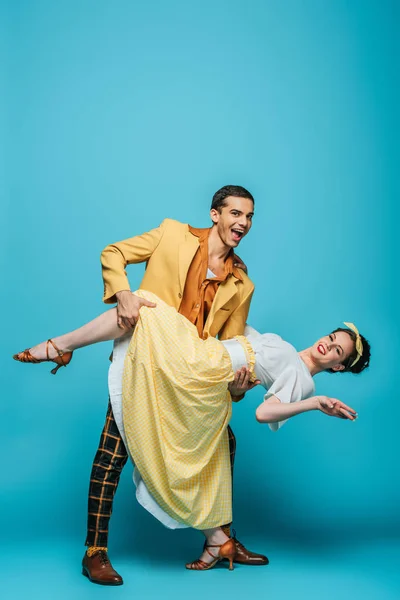 Danseuse souriante soutien fille tout en dansant boogie-woogie sur fond bleu — Photo de stock