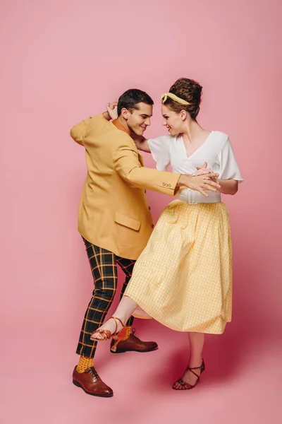 Elegant dancers holding hands while dancing boogie-woogie on pink background — Stock Photo