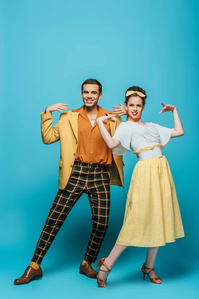 Stylish dancers looking at camera while dancing boogie-woogie on blue background — Stock Photo