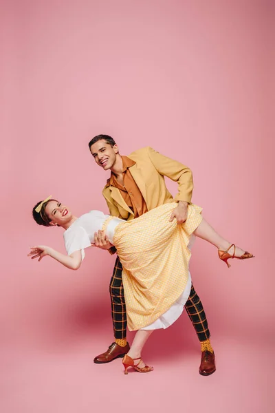 Smiling dancer supporting girl while dancing boogie-woogie on pink background — Stock Photo