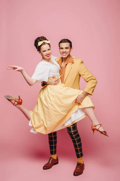 Lächelnde Tänzerin hält Mädchen beim Tanzen Boogie-Woogie auf rosa Hintergrund — Stockfoto