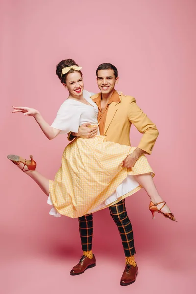 Smiling dancer holding girl while dancing boogie-woogie on pink background — Stock Photo