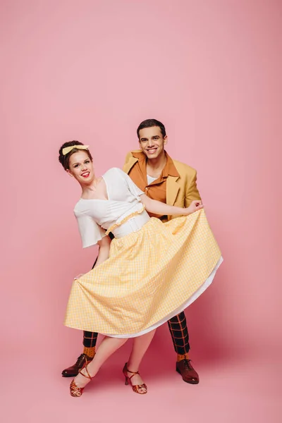 Cheerful dancers looking at camera while dancing boogie-woogie on pink background — Stock Photo