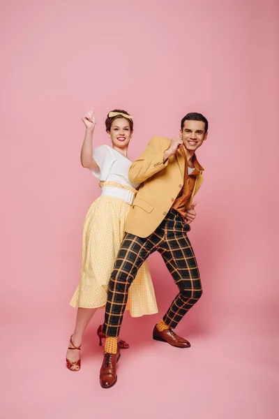 Danseurs gais regardant caméra tout en dansant boogie-woogie sur fond rose — Photo de stock