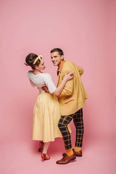 Handsome dancer looking at camera while dancing boogie-woogie with pretty girl on pink background — Stock Photo