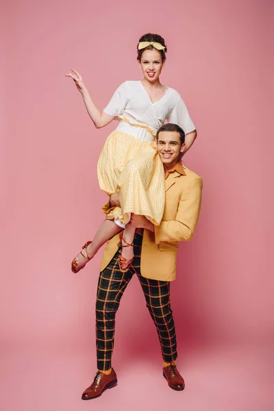 Cheerful man holding happy girl while dancing boogie-woogie on pink background — Stock Photo