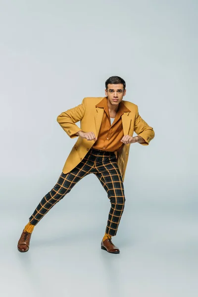 Handsome, stylish dancer looking at camera while dancing boogie-woogie on grey background — Stock Photo