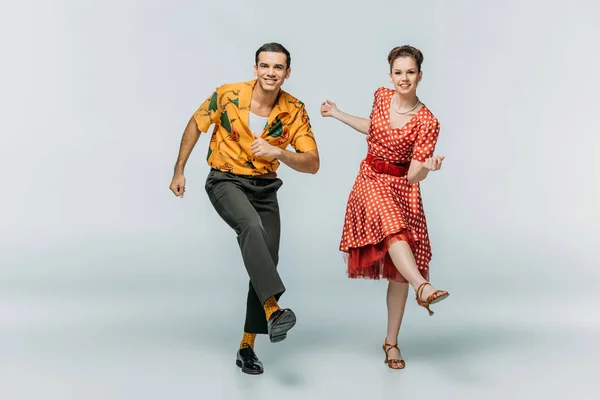 Stylish couple looking at camera while dancing boogie-woogie on grey background — Stock Photo