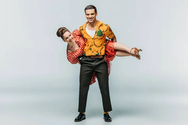 Fröhlicher Mann hält Frau beim Tanzen von Boogie-Woogie auf grauem Hintergrund — Stockfoto