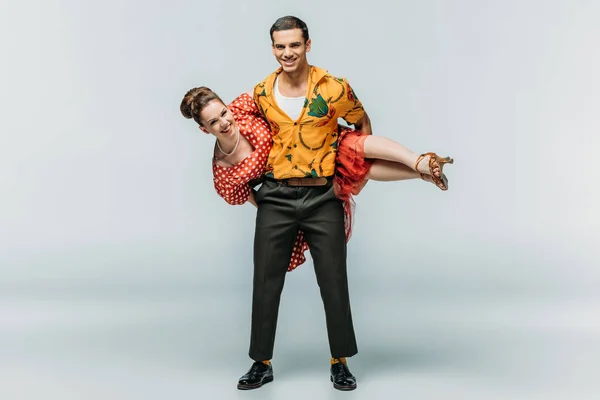 Cheerful man holding woman while dancing boogie-woogie on grey background — Stock Photo